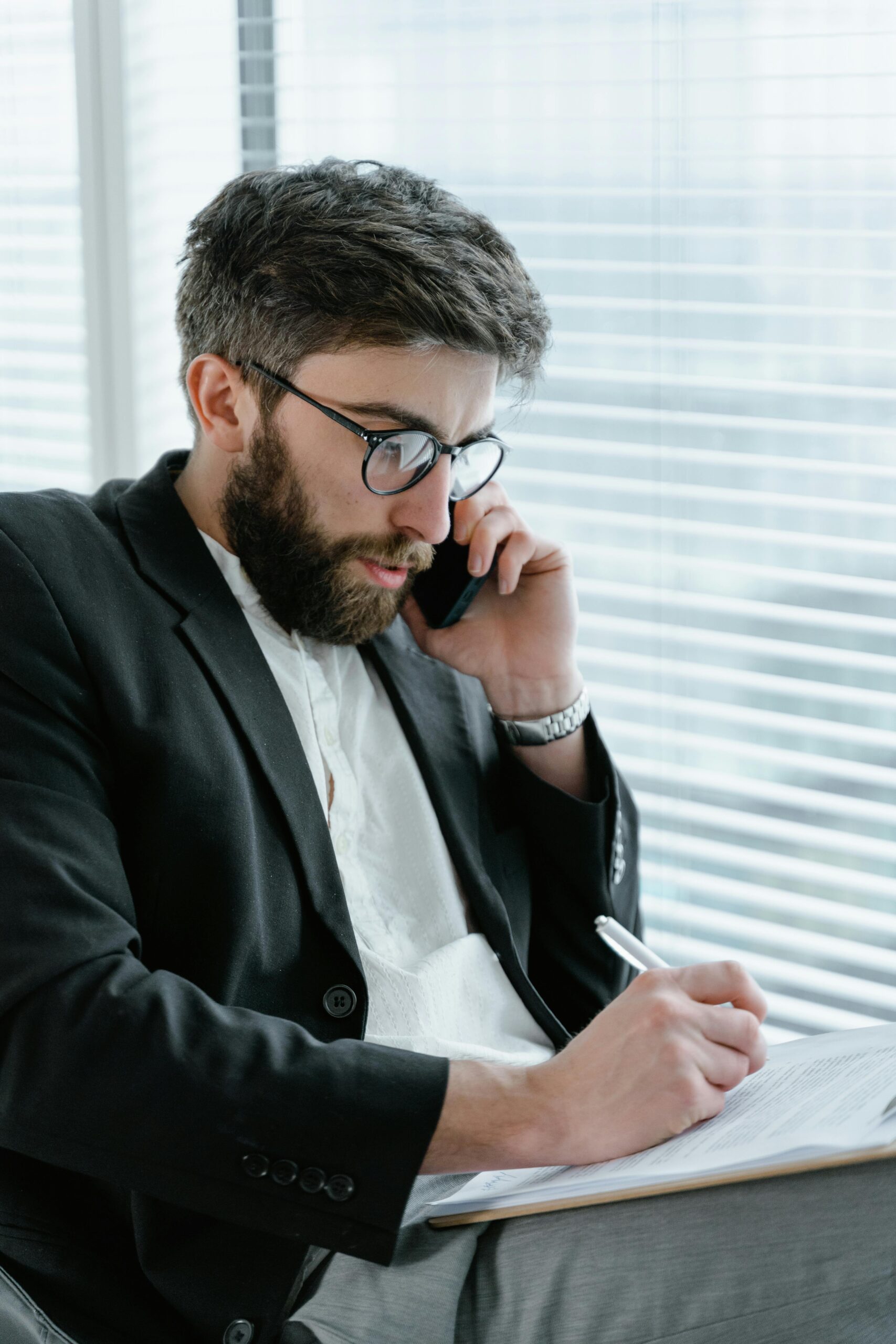 pexels photo 7567553 7567553 1 Focused businessman in office, analyzing documents while on a phone call.